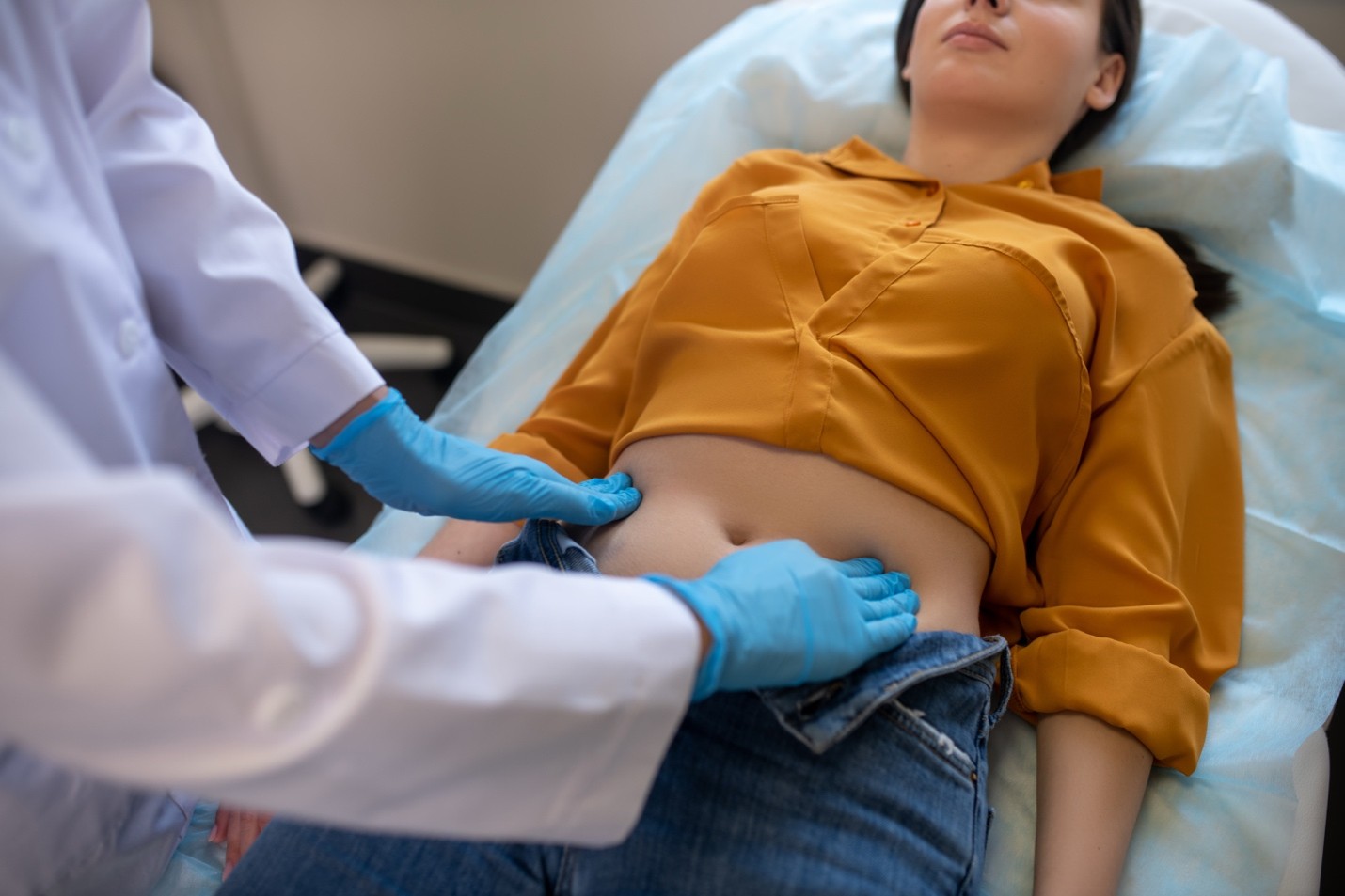 Doctor examinando a una paciente en su zona estomacal.