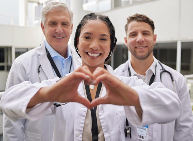 Tres doctores y uno de ellos formando un corazón con sus manos.