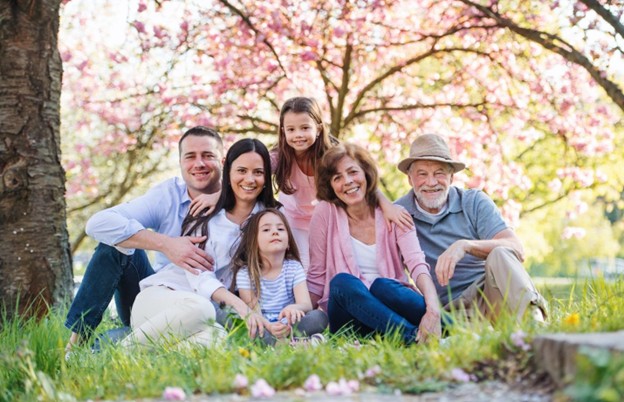 Una familia sentada en un parque sonriendo.