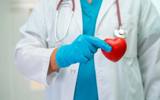 Un médico sostiene un corazón rojo, simbolizando la salud y el cuidado en la medicina.