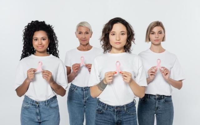Grupo de mujeres sosteniendo un lazo rosado en sus manos.