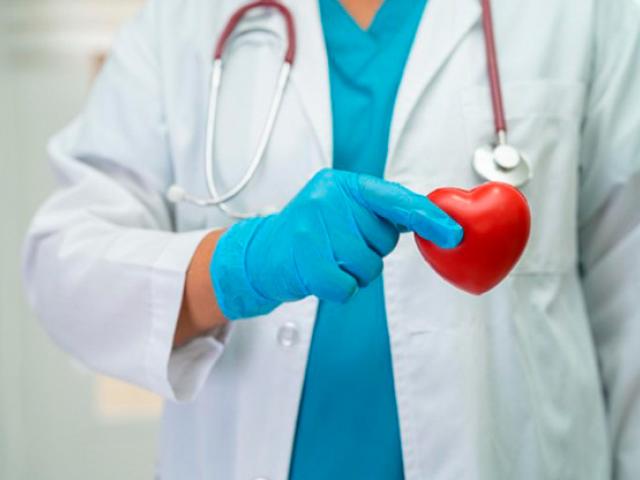 Un médico sostiene un corazón rojo, simbolizando la salud y el cuidado en la medicina.