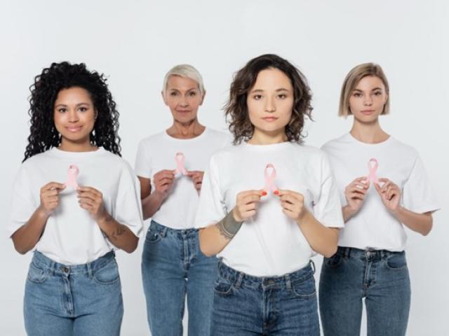 Grupo de mujeres sosteniendo un lazo rosado en sus manos.